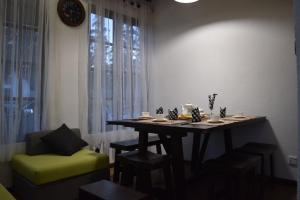 a dining room table with a green chair and a clock at Beraliya Cottage in Nuwara Eliya