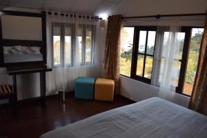 1 dormitorio con cama, ventanas y sofá en Beraliya Cottage en Nuwara Eliya