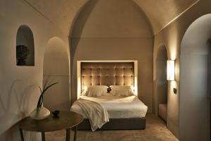 a bedroom with a bed and a table and arches at Sikelia Luxury Hotel in Pantelleria