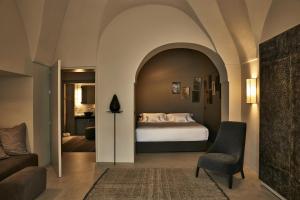 a bedroom with a bed and a couch and a chair at Sikelia Luxury Hotel in Pantelleria