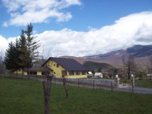 a yellow house in a field with mountains in the background at House Mara in Korenica