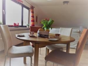 einem Esstisch mit Stühlen und einem Tisch mit Blumen darauf in der Unterkunft Feriendomizil am Rheinbogen in Altlußheim