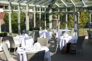 a conservatory with tables and chairs with white table cloth at Flackley Ash Country House Hotel in Rye