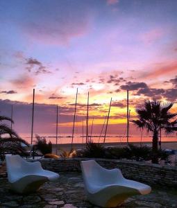 two white chairs sitting in front of a sunset at Albergo Girasole Frontemare in San Benedetto del Tronto
