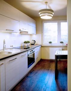 a kitchen with white cabinets and a sink and a table at Apartament Fryderyk Premium 2 in Nysa