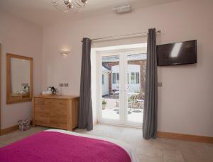 Schlafzimmer mit einem rosa Bett und einer Glasschiebetür in der Unterkunft Mincombe Barn Bed & Breakfast in Sidbury