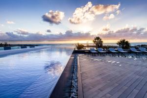 a pool with chairs and the ocean in the background at Barceló Teguise Beach - Adults Only in Costa Teguise