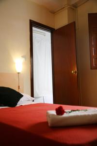 a bedroom with a bed with a red blanket and a window at Pensión Duquesa Bed & Breakfast in Granada