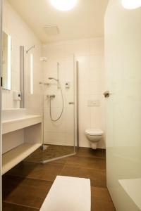 a white bathroom with a shower and a toilet at Hotel Lokomotive in Linz