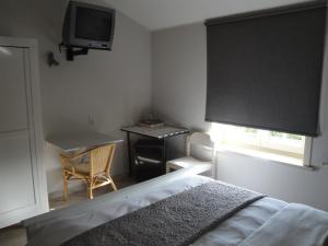 una camera da letto con un letto, una scrivania e una televisione di B&B De Polderhoeve a Blankenberge