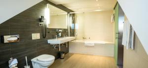 a bathroom with a toilet and a sink and a tub at Hotel Sternen Oerlikon in Zurich