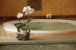 a vase with white flowers on a table next to a bath tub at La Luge D'Antan Maison d'Hôtes & SPA in Brusson