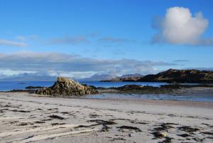 a beach with rocks in the sand and the ocean at Dolphin Hotel in Inishbofin