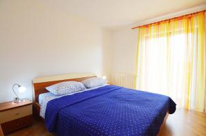 a bedroom with a bed with a blue comforter and a window at Garden Apartment Maria in Vrsar