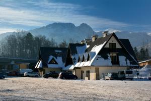 una casa cubierta de nieve con coches aparcados delante en Pokoje pod Gubałówką, en Zakopane