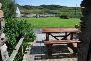 a wooden picnic table sitting on a walkway with a field at Dolphin Hotel in Inishbofin
