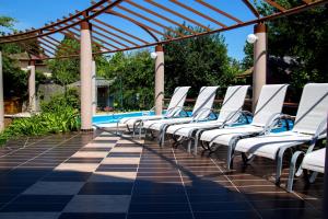 una fila de sillas blancas sentadas junto a una piscina en Princess Apartman, en Siófok