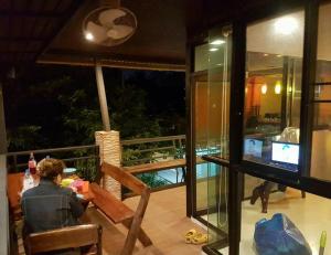 a person sitting in a chair on a balcony watching a television at Kaengkrachan River Hut in Kaeng Krachan