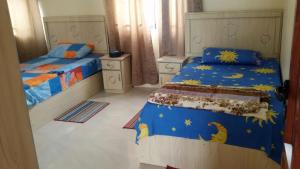 sypialnia z 2 łóżkami z niebieską i żółtą pościelą w obiekcie Kaz Resident w Plaine Magnien
