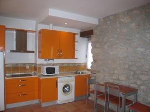 cocina con armarios de color naranja, fregadero y microondas en Apartamentos Puente Viesgo Anjana, en Puente Viesgo