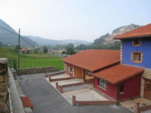 budynek z niebiesko-czerwonym domem obok ulicy w obiekcie Apartamentos Puente Viesgo Anjana w mieście Puente Viesgo