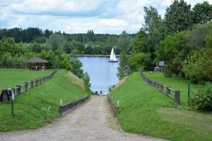 a path next to a lake with a sail boat in the water at Viesu Nams Vecupe in Birzgale