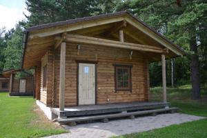 a small log cabin with a porch and a door at Viesu Nams Vecupe in Birzgale +15 photos