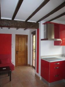 een keuken met rode kasten en een houten deur bij Apartamentos Puente Viesgo Anjana in Puente Viesgo