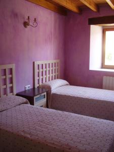 2 camas en una habitación con paredes moradas en Apartamentos Puente Viesgo Anjana, en Puente Viesgo