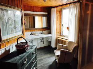 a bathroom with a sink and a chair and a mirror at Auberge de l'Assesseur - Mont-Soleil in Saint-Imier +41 photos