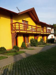 ein gelbes Haus mit einem Balkon an der Seite in der Unterkunft OKKER Apartman in Gyula