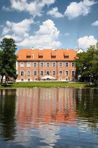 a large brick building next to a body of water at Centrum Konferencyjne Zamek in Szczecinek