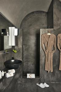 a bathroom with a sink and a robe on a wall at Sikelia Luxury Hotel in Pantelleria