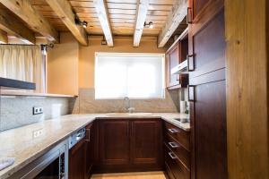 Una cocina con armarios de madera y un fregadero y una ventana. en Apartaments Gran Vall, en La Molina 37 fotos más