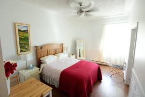 a bedroom with a bed with a red blanket at Auberge le St-Georges in Saguenay