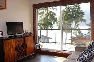a living room with a tv and a large window at Tilby's Rainbow Cottage in Port Renfrew