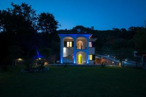 une maison bleue avec une horloge la nuit dans l'établissement Incanto di Luna, à Ispani