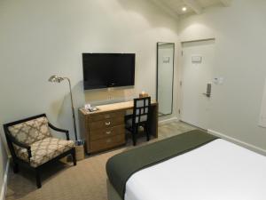 ロサンゼルスにあるBrentwood Innのベッド、デスク、テレビが備わるホテルルームです。