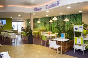 a restaurant with tables and chairs and a wall with plants at ibis styles Villeneuve Sur Lot in Villeneuve-sur-Lot