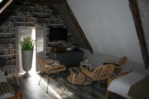 a living room with wicker chairs and a tv at Het Huis van de Wadden in Den Oever