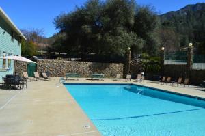 a swimming pool with chairs and a person walking by it at Cedar Lodge in El Portal
