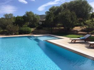 a swimming pool with a bench and a chair next to it at Le Tre Pietre in Baja Sardinia