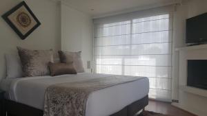 a bedroom with a large white bed and a window at Suites 109 GH Usaquén in Bogotá