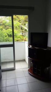 a living room with a tv and a window at Ubatuba Apartamento Maurilio in Ubatuba