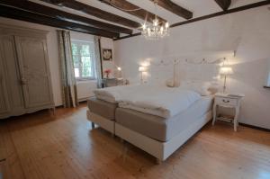 Un dormitorio con una gran cama blanca y una lámpara de araña. en Gästehaus Wahnenmühle en Erkrath