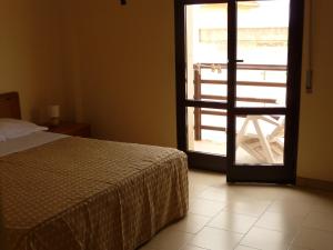 um quarto com uma cama e uma porta aberta em Agathae Hotel & Residence em Scoglitti