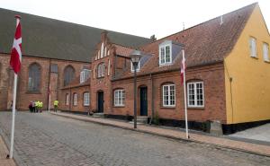 马里博PilgrimsHuset Maribo的街上一排挂着旗帜的砖砌建筑