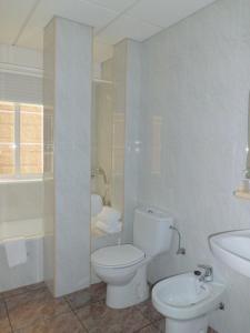 a white bathroom with a toilet and a sink at Hotel Brisa in A Lanzada