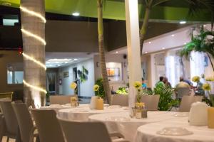 uma sala de jantar com mesas e cadeiras brancas e palmeiras em Hotel de Casa Blanca em Lázaro Cárdenas