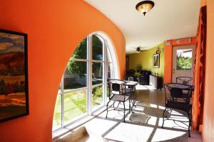 een oranje kamer met tafels en stoelen en een groot raam bij Auberge le St-Georges in Saguenay
